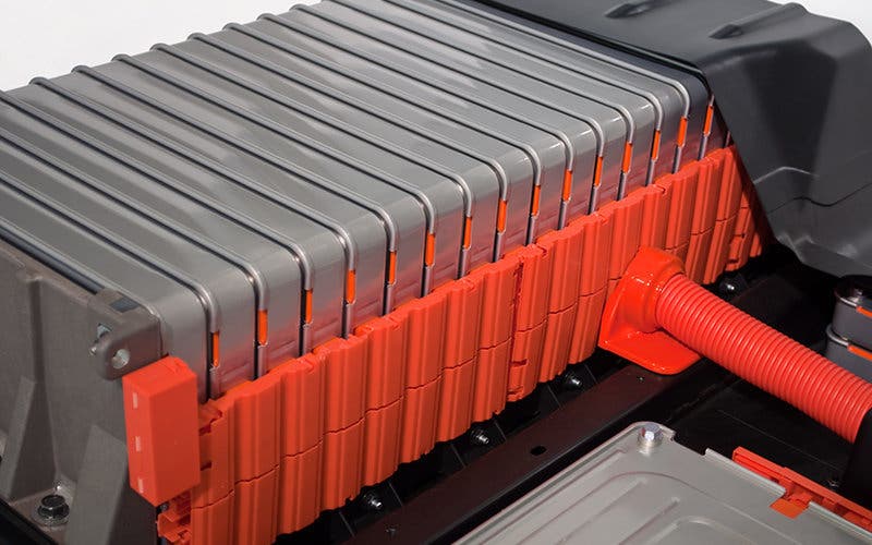 Batteries loaded in a row on an electric car. Each battery pack is stacked in an orange plastic case. 
