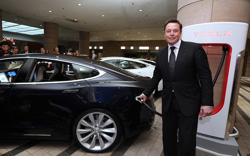 Elon Musk, co-founder and chief executive officer of Tesla Motors Inc., holds the charging nozzle as he demonstrates the company's Model S electric sedan following a news conference in Tokyo, Japan, on Monday, Sept. 8, 2014. Tesla may partner with Toyota Motor Corp. again in the future, Musk said. Photographer: Yuriko Nakao/Bloomberg *** Local Caption *** Elon Musk