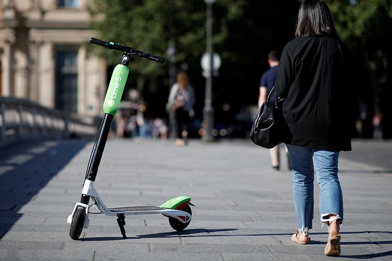 FILE PHOTO: A woman walks past a dock-free electric scooter Lime-S by California-based bicycle sharing service Lime displayed on their launch day in Paris, France, June 22, 2018. REUTERS/Benoit Tessier/File Photo
