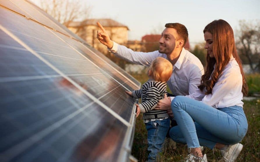 Side view shot of a young modern family with a little baby boy getting acquainted with solar panel on a sunny day, green alternative energy concept