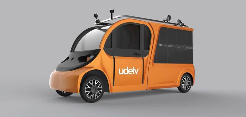 The distinctive orange udelv customized vehicle is built on a fully electric powertrain and features 18 secure cargo compartments with automatic doors using a cloud-based proprietary technology that is shared between the vehicle, customers and merchants.  The vehicle can drive for up to 60 miles per cycle and can load up to 700 pounds of cargo. (PRNewsfoto/udelv)