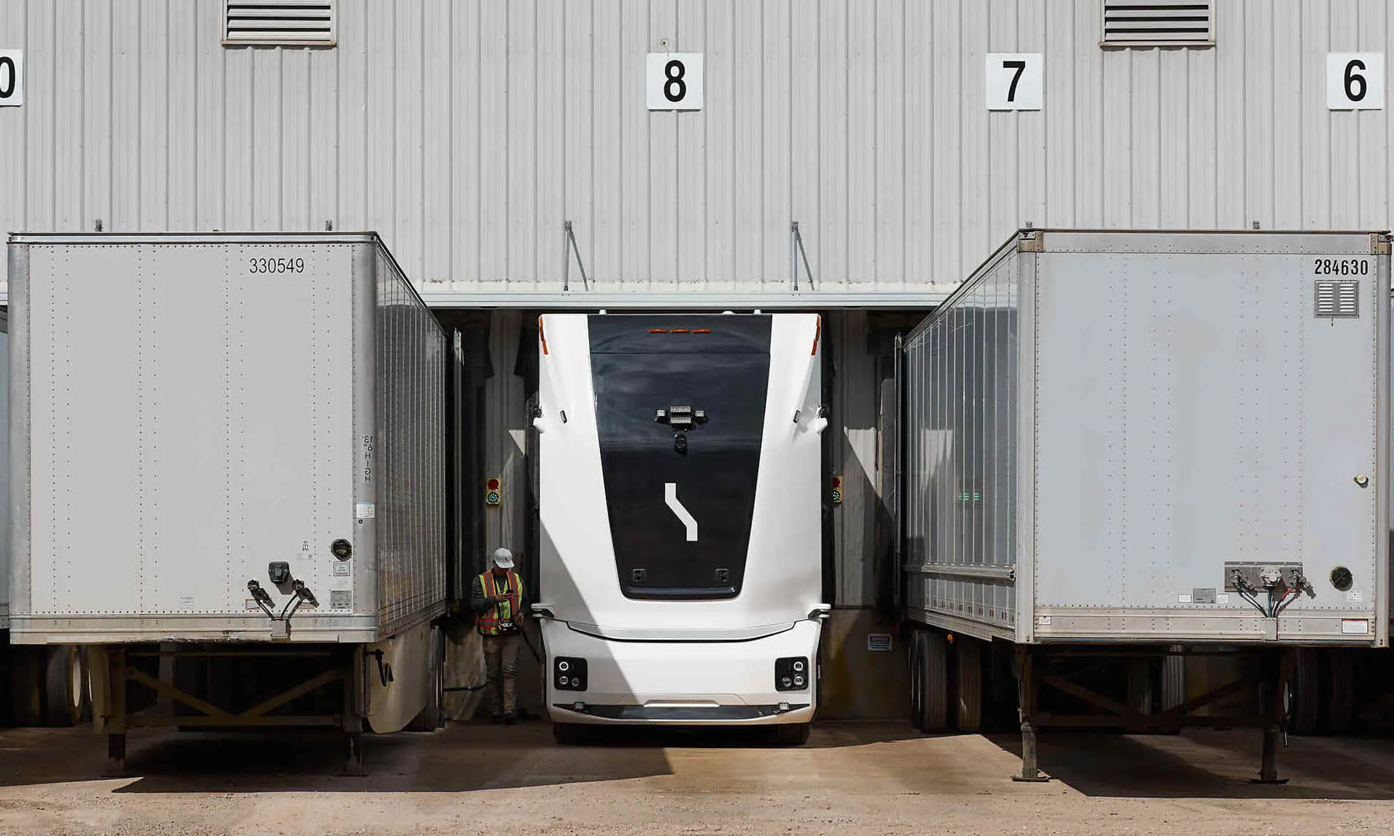 El camión eléctrico y autónomo transporta mercancías entre una fábrica y un almacén.